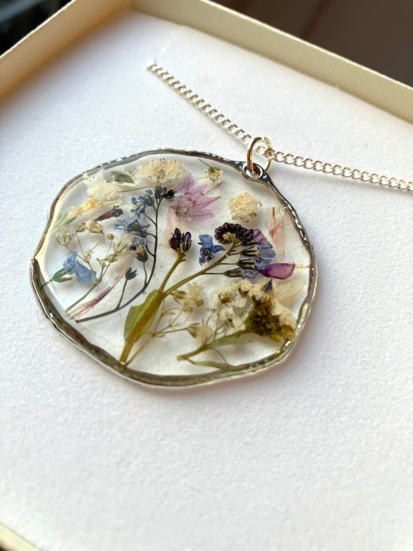 Real pressed flower necklace. Forget me nots, baby’s breath, blossom, In silver with a silver chain. 40mm size.